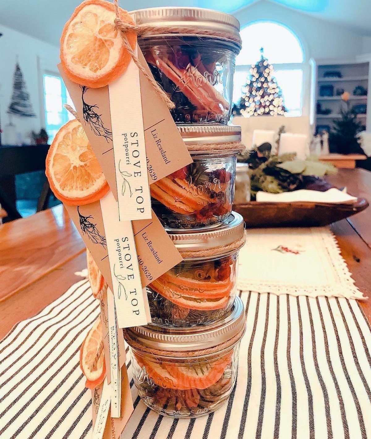 Stacked glass jars of stove top potpourri with dried oranges and cinnamon sticks.