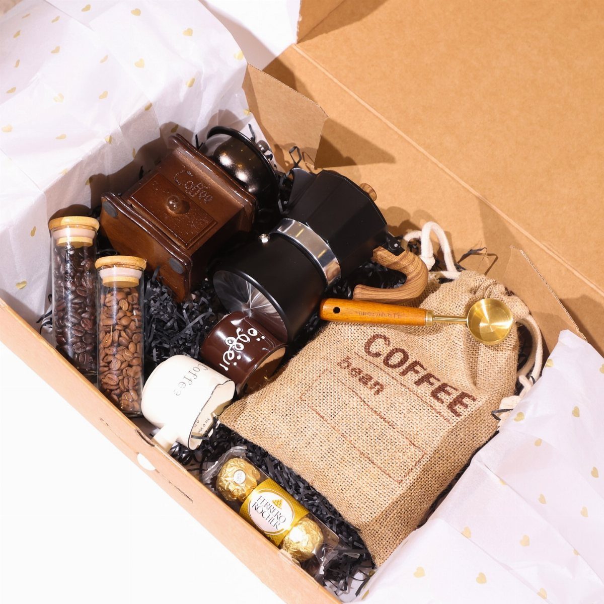 Coffee gift basket containing a grinder, moka pot, beans, and a burlap bag.