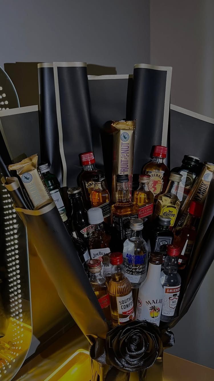 Miniature liquor bottles arranged as a bouquet wrapped in black and gold paper.